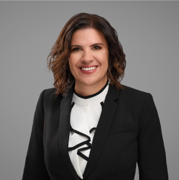 Portrait of smiling woman in a professional attire against a grey background.